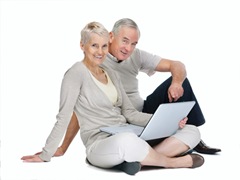 Studio image of casual old couple sitting with laptop on white